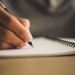 Man hand with pen writing on notebook.