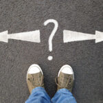 feet standing on asphalt with arrows pointing left and right with question mark