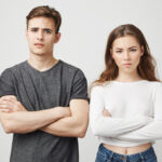 Two people standing in poses looking disappointed. Friends angry at their pal because they waited him for hours and he did not come. He apoogized telling he fell asleep but they do not believe him
