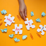 Puzzles with letters, papers, paper clips and hand on orange bac