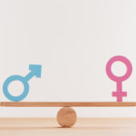 Blue man sign and pink woman sign on balance wooden seesaws for