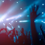 silhouettes of hand in concert.Light from the stage.