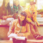 high school student girl reading book outdoors