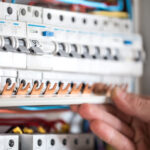 Man, an electrical technician working in a switchboard with fuse